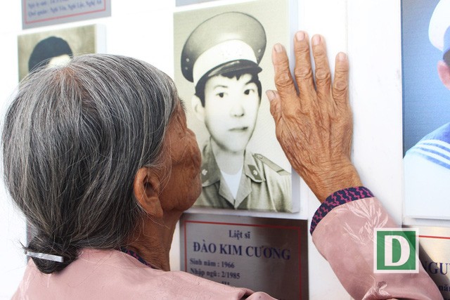 Mẹ liệt sĩ Đào Kim Cương (Hà Tĩnh) run run đặt bàn tay lên di ảnh con tại Khu tưởng niệm Chiến sĩ Gạc Ma