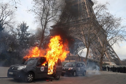 Xe quân sự chống khủng bố bị người biểu tình đốt gần Tháp Eiffel hôm 9/2. Ảnh: AFP.